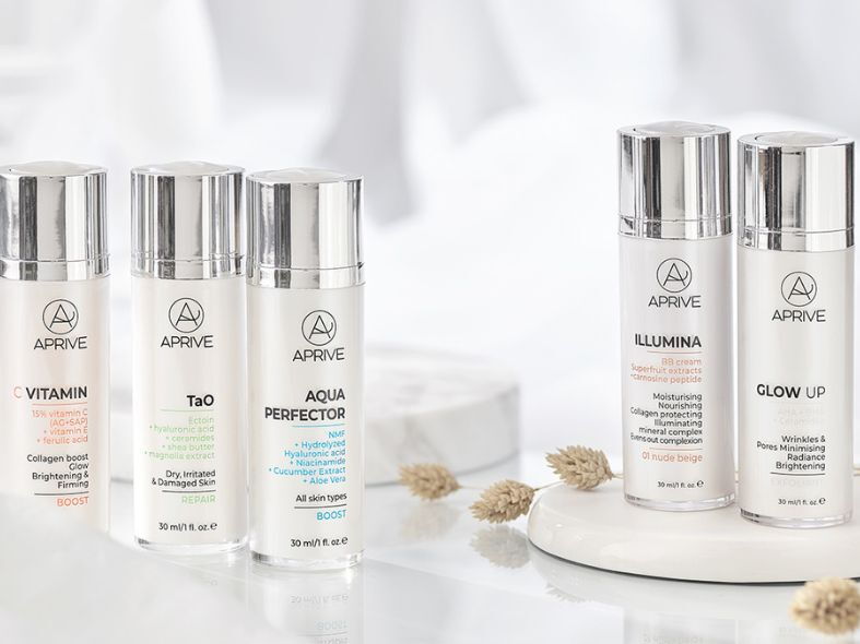 Five APRIVE clean beauty skincare bottles including Vitamin C serum, moisturizers, and BB cream arranged on a minimalist white surface.
