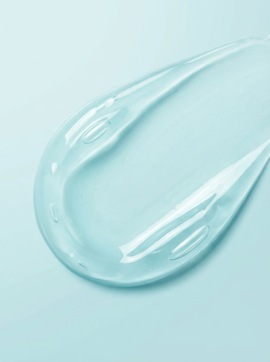 A close-up view of a clear, light blue beta-glucan skincare gel smear with bubbles on a blue background.