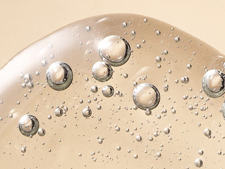 Close-up texture of a clear hyaluronic acid serum with bubbles.