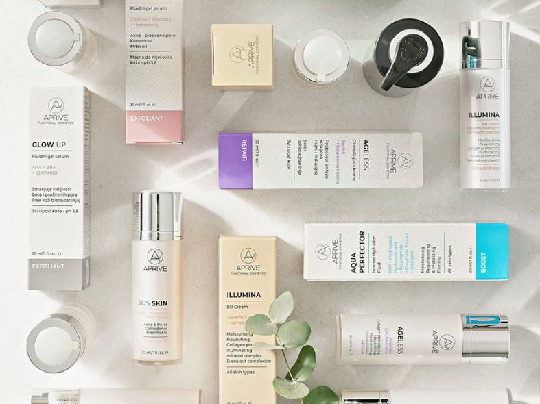 Flat lay overview of Aprive Functional Cosmetics products including serums, creams, and exfoliants with natural ingredients like eucalyptus on a stone surface.