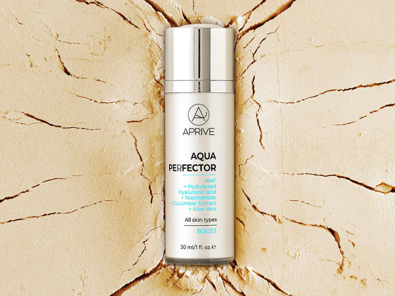 Bottle of Aprive Aqua Perfector Boost serum with hyaluronic acid and niacinamide placed on a cracked, dry earth background representing dehydrated skin.