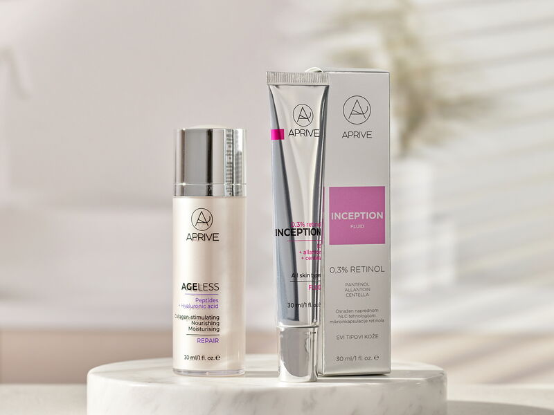 Aprive Inception 0.3% Retinol Fluid tube with box and Ageless Peptides + Hyaluronic Acid Repair serum bottle displayed on a white marble podium.