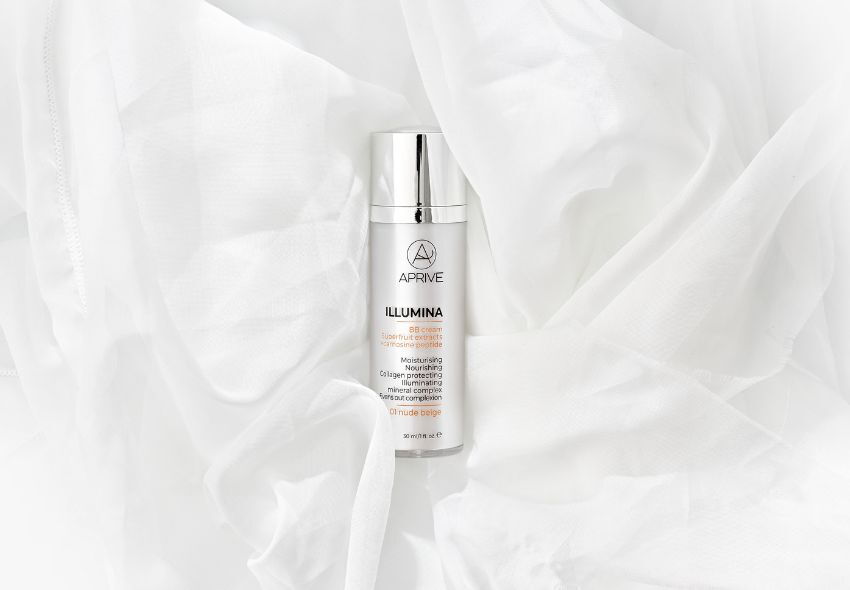 Bočica APRIVE ILLUMINA BB kreme u nijansi 01 nude beige na mekoj bijeloj tkanini.