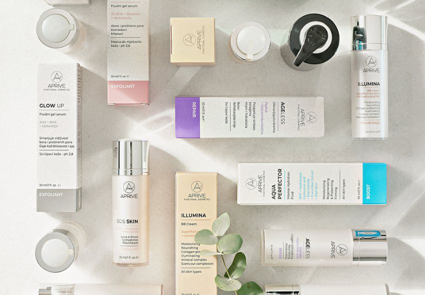 Flat lay pregled proizvoda Aprive funkcionalne kozmetike uključujući serume, kreme i pilinge s prirodnim sastojcima poput eukaliptusa na kamenoj površini.