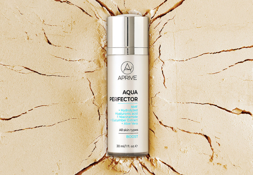 Bočica Aprive Aqua Perfector Boost seruma s hijaluronskom kiselinom i niacinamidom na ispucadoj, suhoj zemlji koja predstavlja dehidriranu kožu.